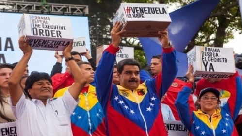 Venezuelan President Nicolas Maduro (middle) holds aloft boxes of petitions signed by millions demanding U.S. President Obama withdraw sanctions. 