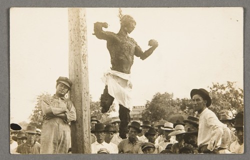 Lynchers often paraded their victim down the main street, through black neighbourhoods, and in front of "colored schools" that were in session. Jesse Washington, seventeen years old, was the chief suspect in the May 8, 1916, murder of Lucy Fryer of Robinson, Texas, on whose farm he worked as a labourer. After the lynching, Washington's corpse was placed in a burlap bag and dragged around City Hall Plaza, through the main streets of Waco, and seven miles to Robinson, where a large black population resided. His charred corpse was hung for public display in front of a blacksmith shop. The sender of this card, Joe Meyers, an oiler at the Bellmead car department and a Waco resident, marked his photo with a cross (now an ink smudge to left of victim). From the exhibition “Without Sanctuary: Lynching Photography in America.” Photo courtesy of The New-York Historical Society.